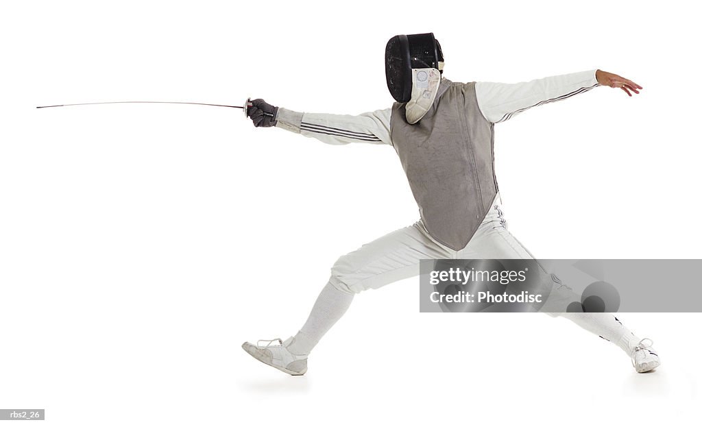 A caucasian male wearing a mask and protective gear lunges forward with his sword while fencing