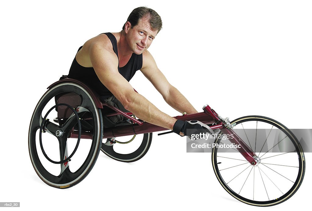 An adult caucasian male wheelchair racer in a black tank top sits in his wheelchair and grips the base