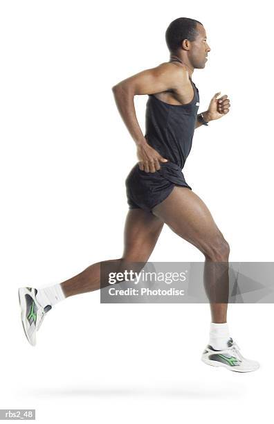 a male african american runner wearing black shorts and shirt is running in profile to the camera - running shorts foto e immagini stock