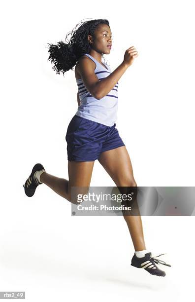 a female african american runner wearing blue has long hair as she jogs in profile to the camera - laufen freisteller stock-fotos und bilder