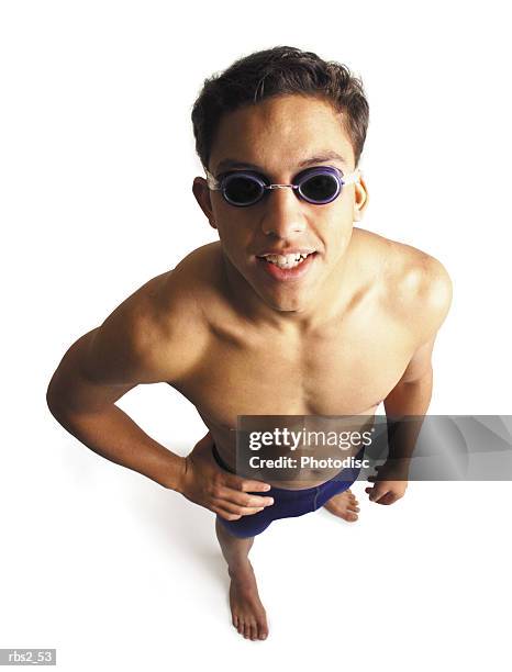 a male swimmer wearing blue racing trunks and goggles looks up at the camera smiling - young men in speedos 個照片及圖片檔