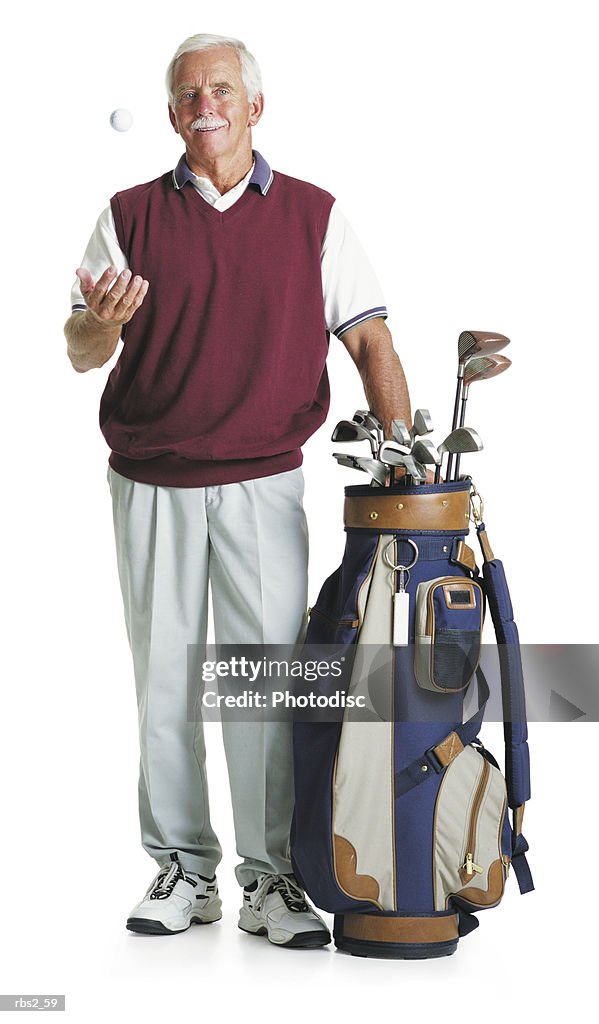 Elderly caucasian man moustache wears maroon vest white slacks stands by golf bag tosses a golf ball