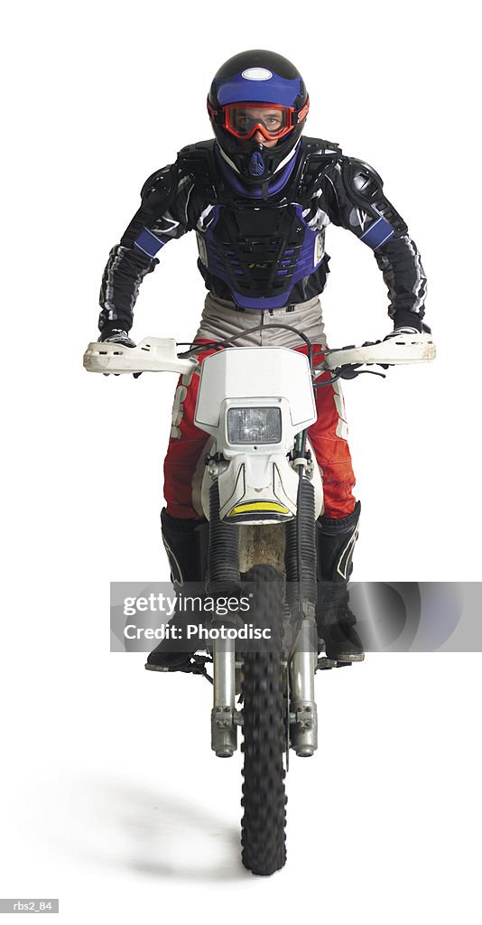 A young caucasian male dirtbiker sits upon his motorcycle and races forward