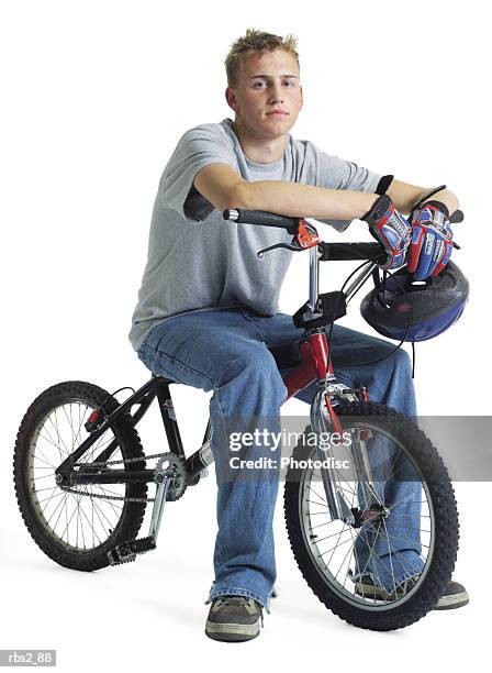 a caucasian teenage boy is sitting on his stunt bike resting as he holds his bike helmet across the handlebars - across stock pictures, royalty-free photos & images