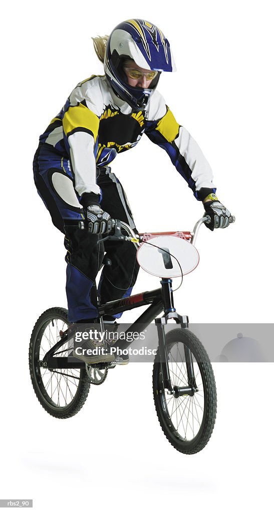 A blond caucasian teenage girl wearing a bike racing suit and helmet is airborne on her dirtbike