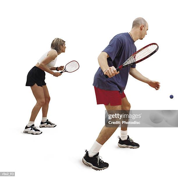 a caucasian man and woman are facing towards the side as they hold rakets and play raketball - racketball stock pictures, royalty-free photos & images