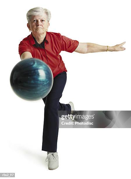 an elderly caucasian woman with white hair runs toward the camera wearing a red shirt and about to throw her blue bowling ball - white shirt ストックフォトと画像