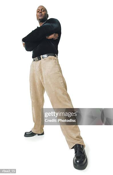 low angle shot of an african american man in tan pants and a black shirt as he folds his arms and smiles - low angle view man stock pictures, royalty-free photos & images