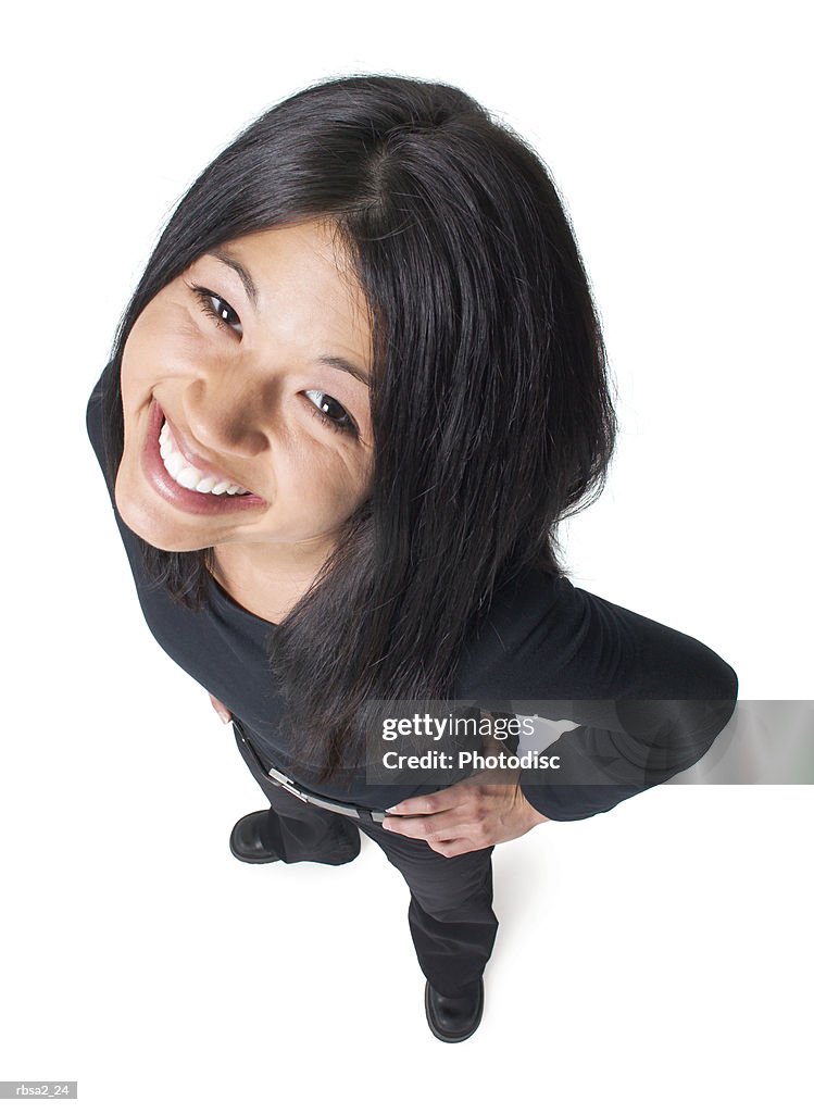 A young attractive asian woman dressed in black puts her hands on her hips and smiles up at the camera