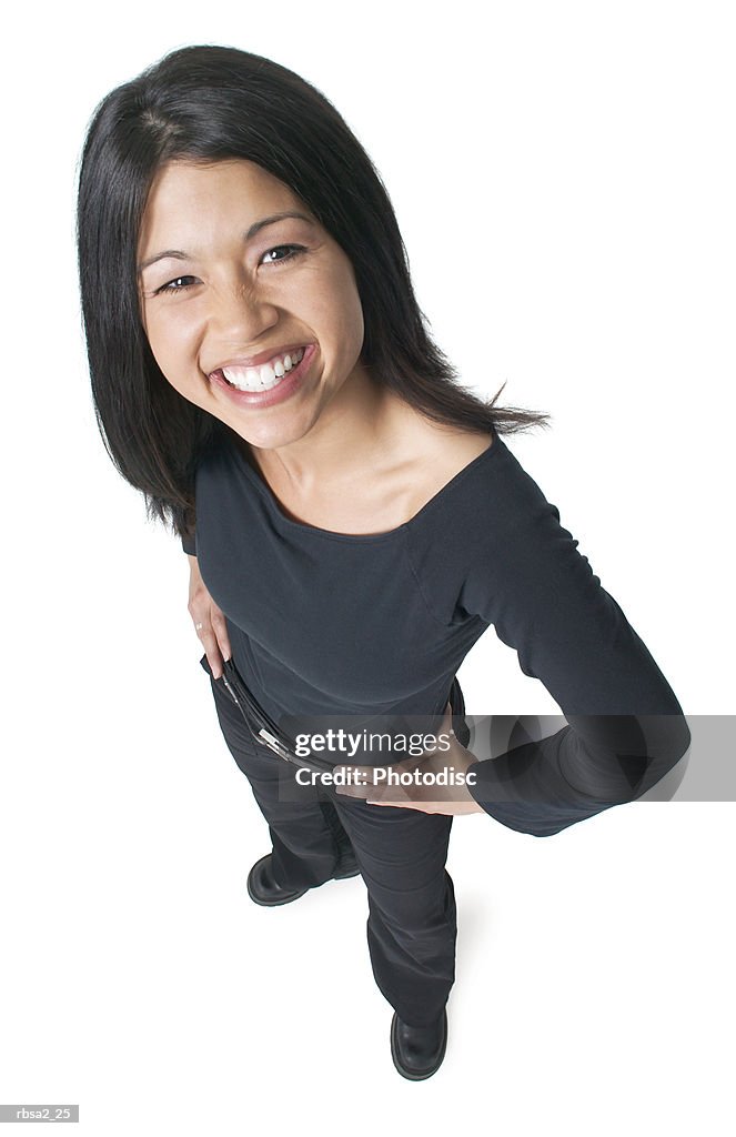 Young attractive asian woman dressed in black puts her hands on her hips and smiles up to the camera