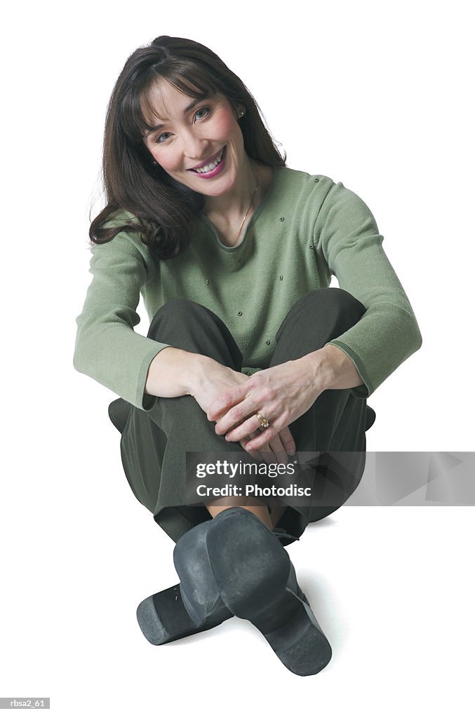 A caucasian woman dressed in green pants and blouse sits down and smiles