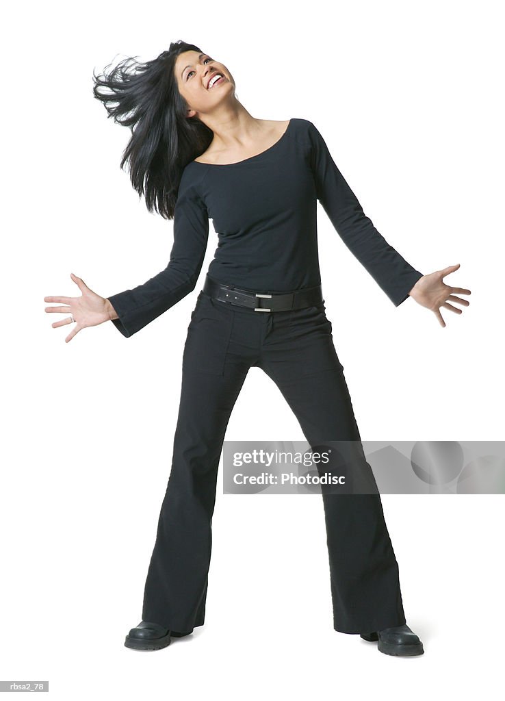 A young attractive asian woman dresses in black dances playfully and tosses her hair to the side