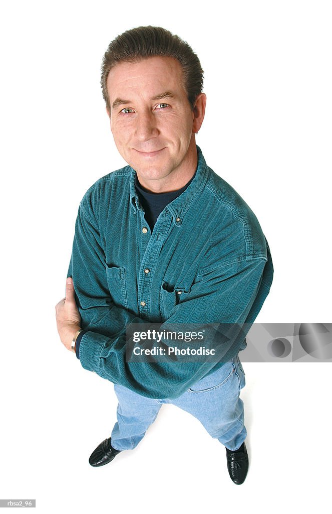 An adult caucasian man in jeans and a green shirt folds his arms and smiles up at the camera