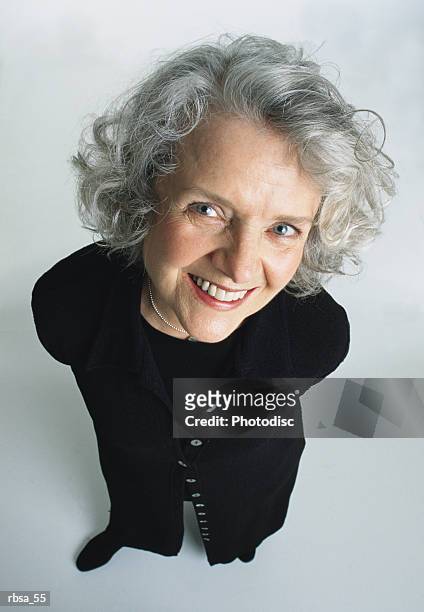 old pretty caucasian adult female with white curly hair and blue eyes wears a dark trendy sweater dress and looks up at the camera smiling warmly - curly stock pictures, royalty-free photos & images