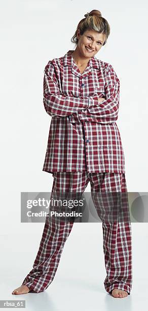 pretty young caucasian adult blonde female barefoot with hair up wearing red plaid pajamas stands with arms folded looking at the camera with a humorous smile - smile stock-fotos und bilder