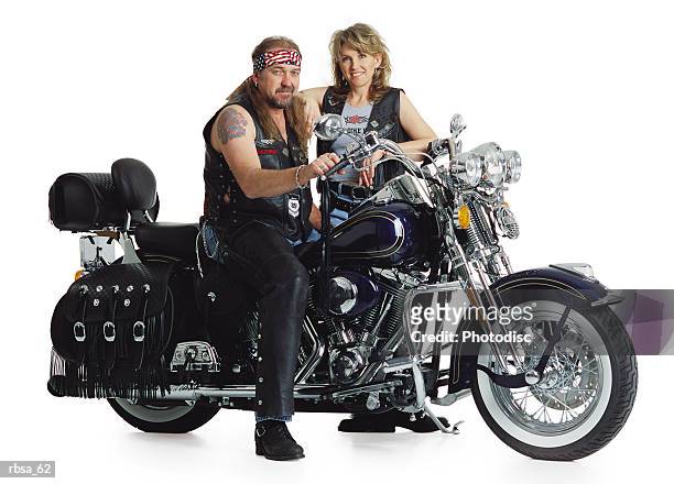 middle aged adult caucasian male motorcycle middle aged adult blonde caucasian female stands behind - leather vest stock-fotos und bilder