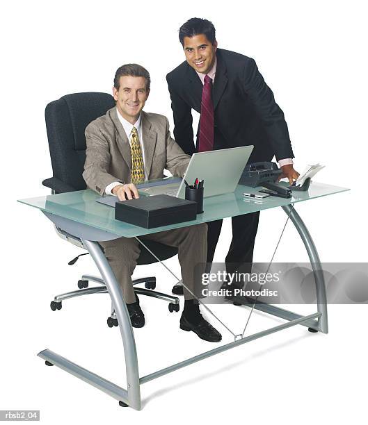 a caucasian business man sits at his desk and converses with a coworker as they both smile - smile stockfoto's en -beelden