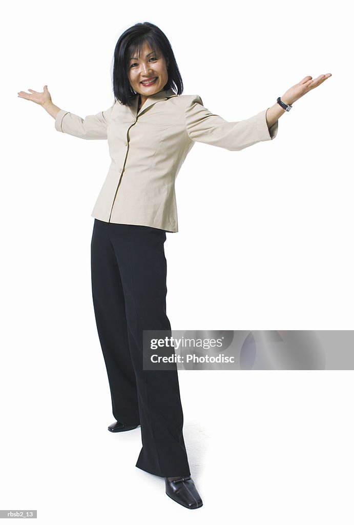 An asian woman in black pants and a tan blouse holds her arms out and smiles