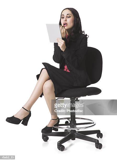 a young ethnic business woman sits on a chair and fixes her make up - make up ストックフォトと画像