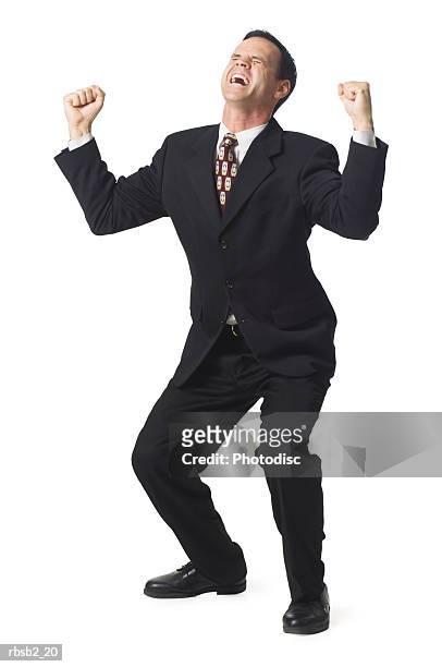 a caucasian business man in a dark suit holds up his arms in celebration - celebration imagens e fotografias de stock