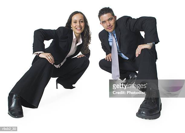 two ethnic business people crouch down in a fun action pose and smile - smile stockfoto's en -beelden