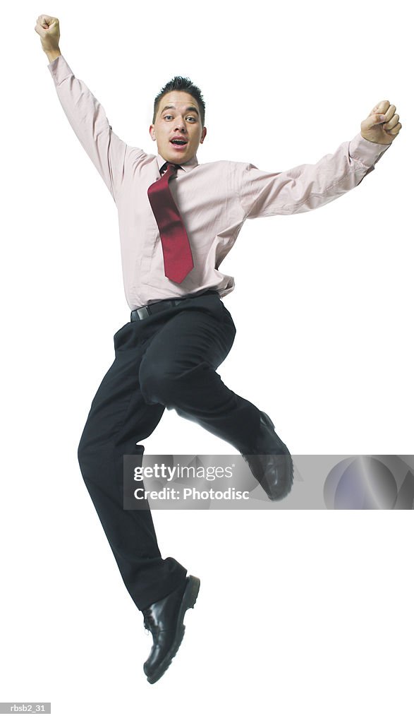 A hispanic business man in a pink shirt and tie jumps playfully up into the air