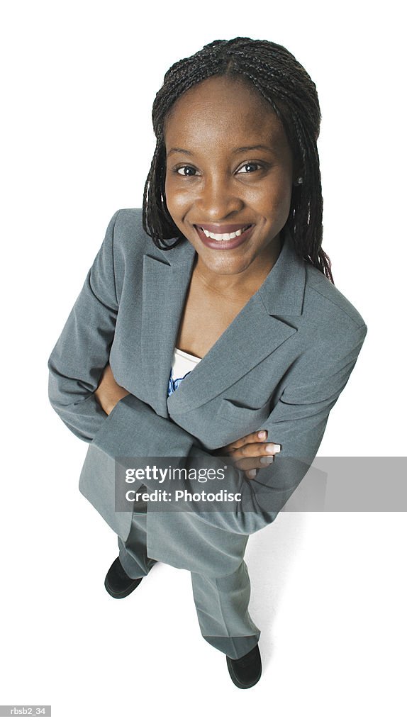 An attractive african american business woman in a grey pant suit folds her arms and smiles up at the camera