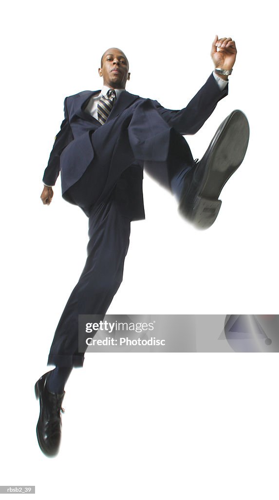 Low angle of an african american business man in a dark suit as he jumps through the air
