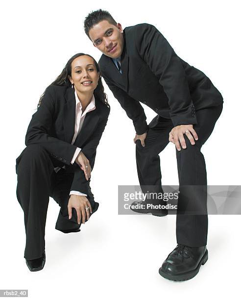 two young ethnic business people crouch down and smile at the camera - smile stockfoto's en -beelden