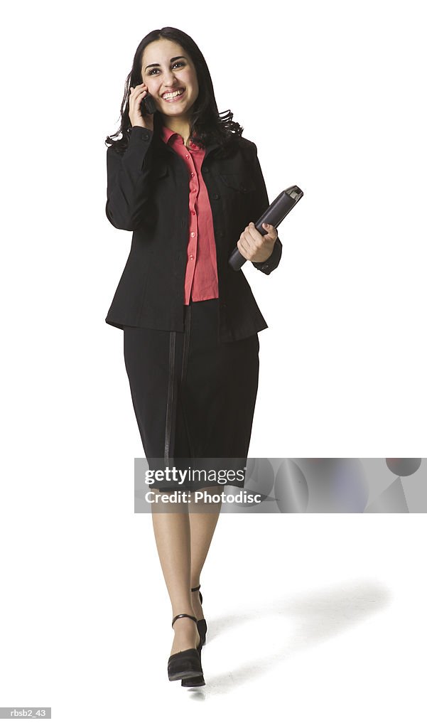 An attractive hispanic business woman walks as she talks on her cell phone