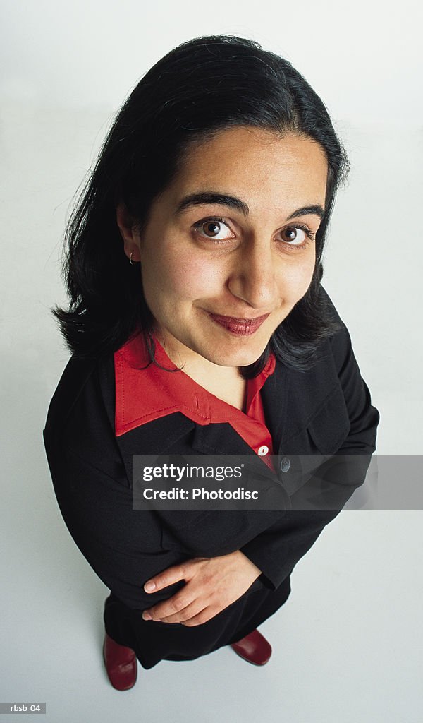 Young beautiful ethnic woman with long dark hair in a dark suit looks to camera arms crossed