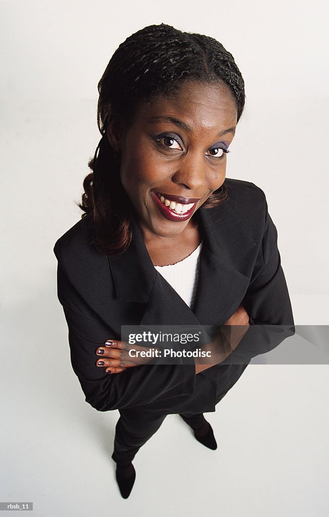 Attractive young african american woman long dark hair dark suit stands looks to camera arms crossed
