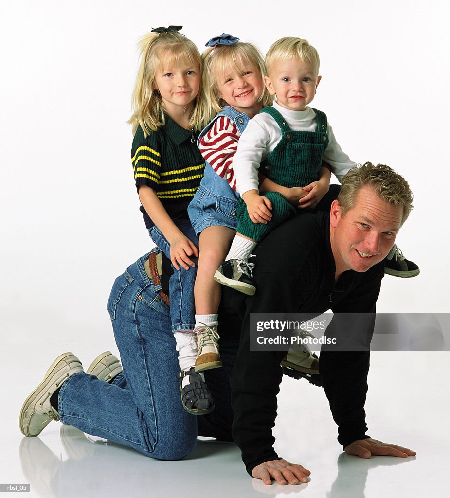 Caucasian dad giving three small blonde children a ride on his back