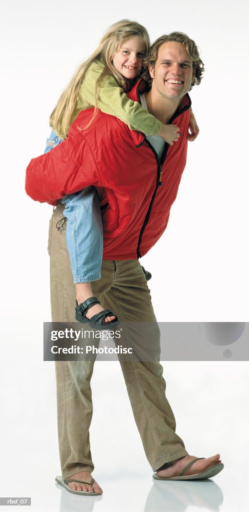 Blonde caucasian dad in red jacket gives a blonde long haired daughter a piggy-back ride