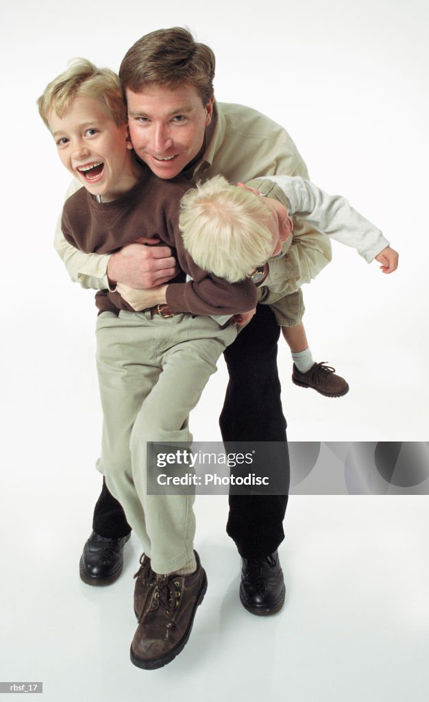 Caucasian single father plays with two laughing blonde boys