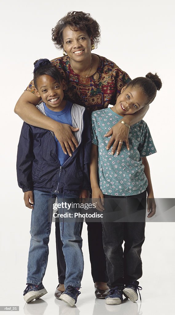 Happy african american mom stands behind her two daughters