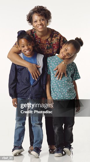 Happy african american mom stands behind her two daughters Happy african american mom stands behind her two daughters