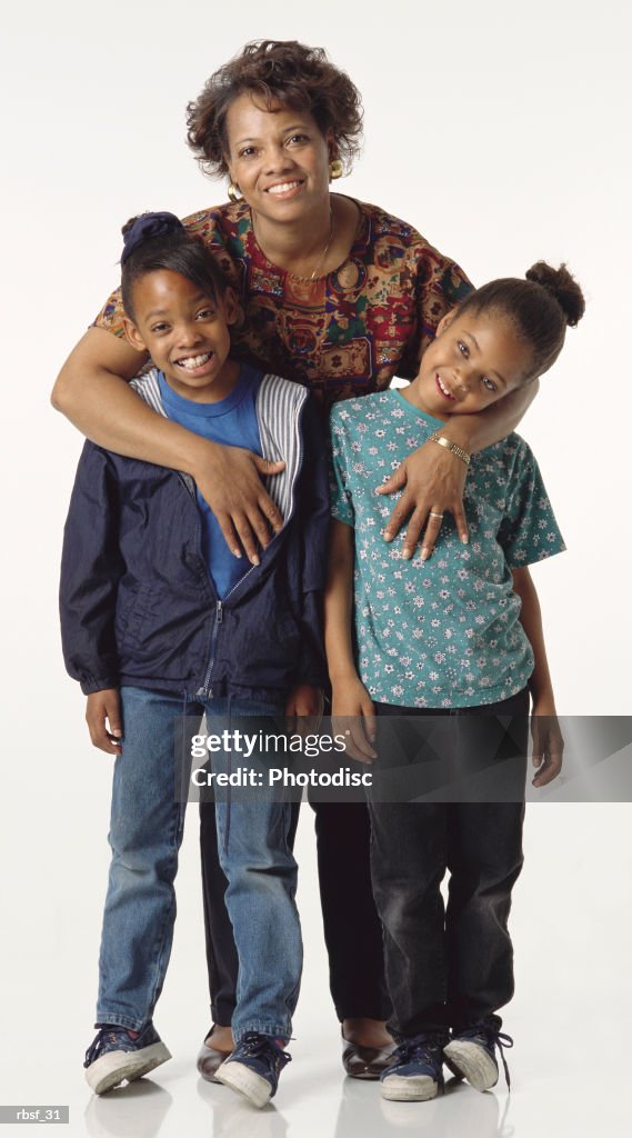 Happy african american mom stands behind her two daughters