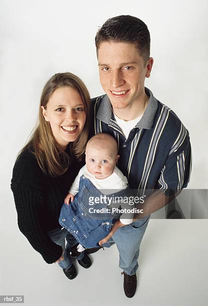 a happy brown haired young caucasian couple holds their infant - happy stockfoto's en -beelden