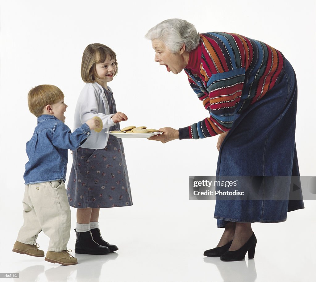 Caucasian young kids get cookies from grandma and giggle