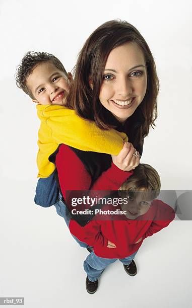 young caucasian single mom with one kid in yellow on her back and one kid in red with hands on hips standing next to her - next imagens e fotografias de stock