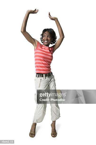 a young adult female in tan pants and a striped shirt puts up her arms and dances playfully - tan tan stock pictures, royalty-free photos & images