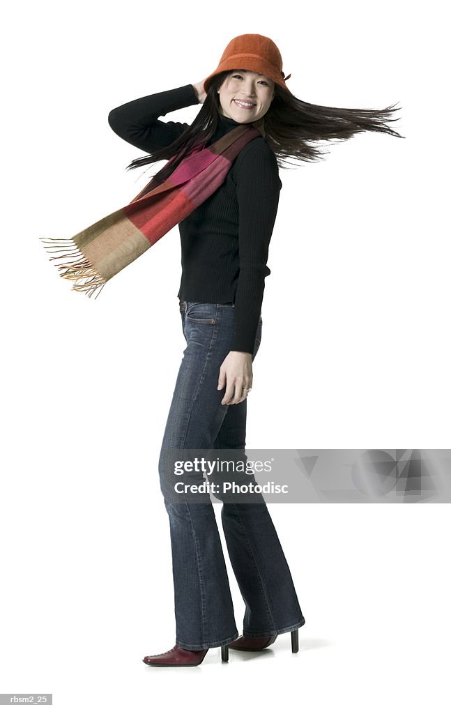 A young adult female in a hat and scarf spins around playfully