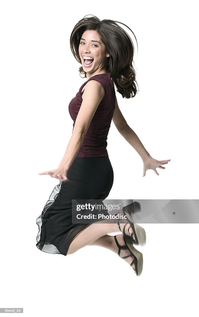 A young adult female in black skirt and burgundy blouse jumps up in the air and smiles brightly