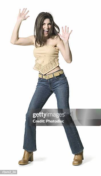 a young adult female in jeans and a tan shirt dances around and holds up her arms - tan tan stock pictures, royalty-free photos & images