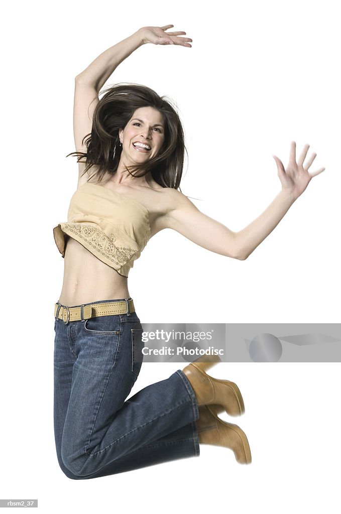 A young adult female in jeans and a tan shirt dances jumps up wildly into the air