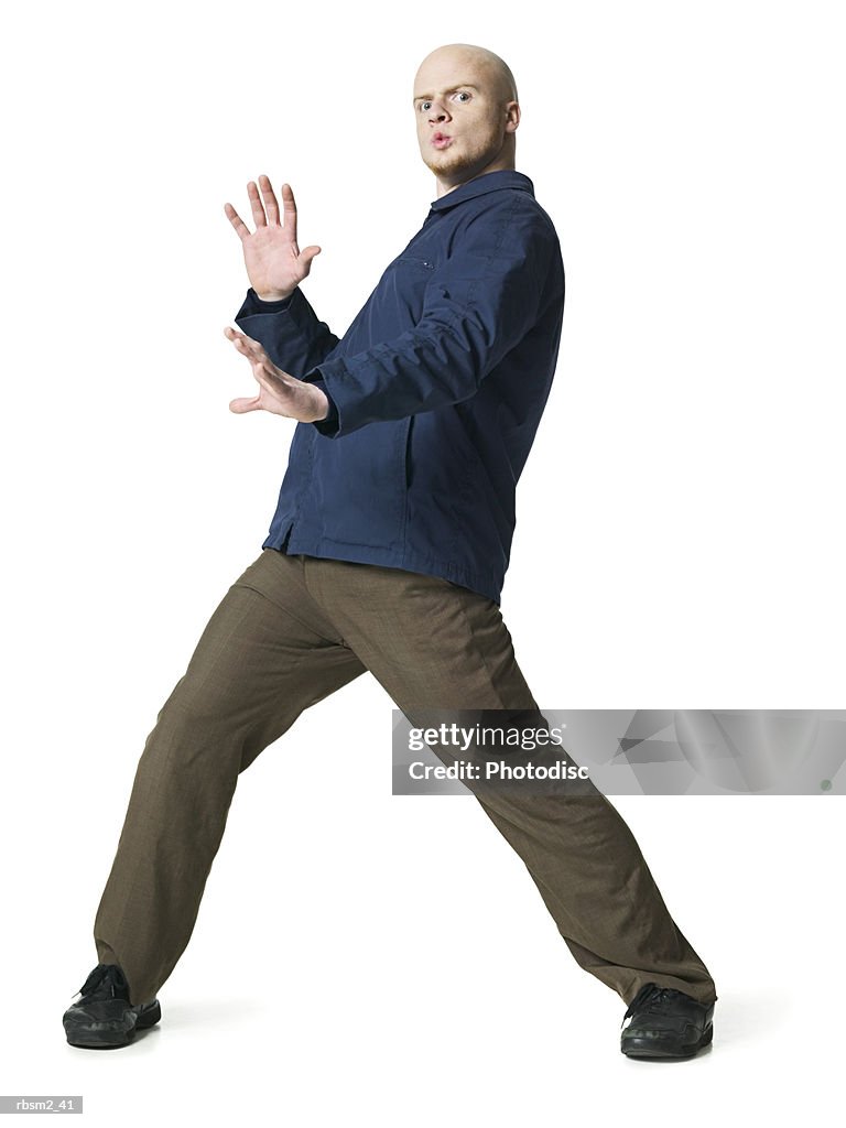 A young adult male in brown pants and a blue jacket dances around playfully