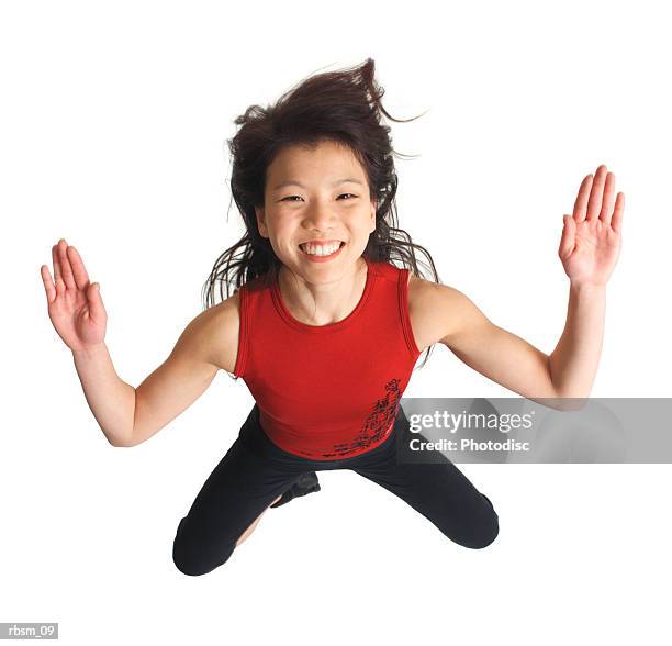 overhead view of an attractive asian girl in a red tank top and black pants crouched down and spreads her arms out as she looks up into the camera - pants down bildbanksfoton och bilder
