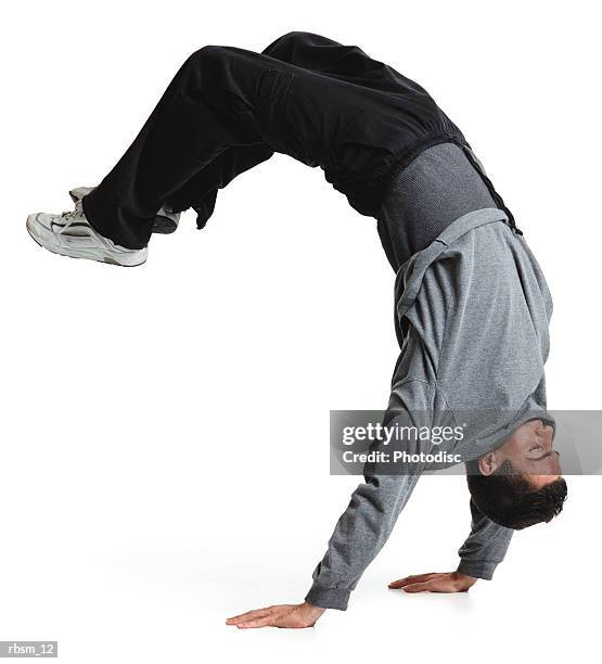 young male breakdancer black pants and grey sweatshirt flips upside down and balances on his hands - pants down bildbanksfoton och bilder