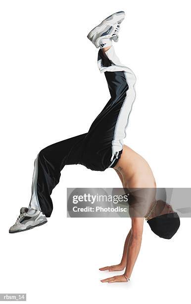 a young caucasian male breakdancer in black pants and no shirt and a knit cap is flipped upside down balancing on his hands with his legs in the air - no stock pictures, royalty-free photos & images